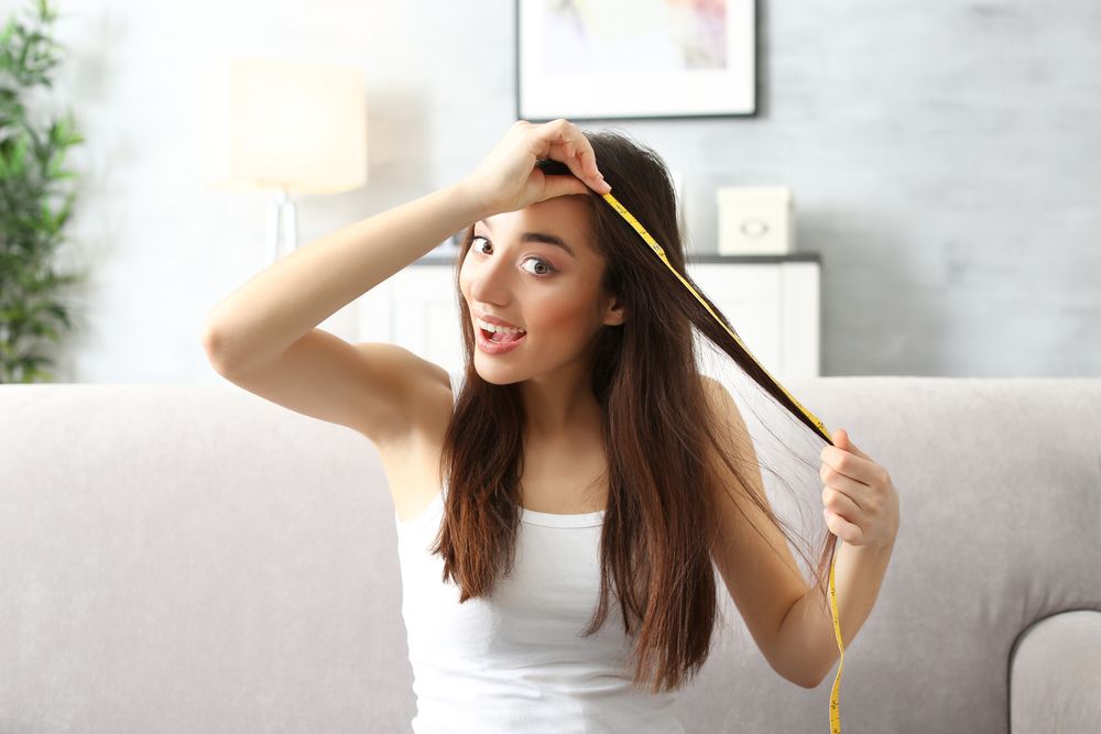 Young woman measuring hair length at home