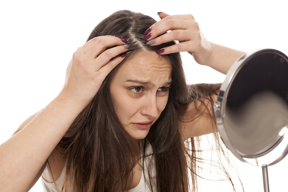 young nervous woman looks at her hair in the mirror