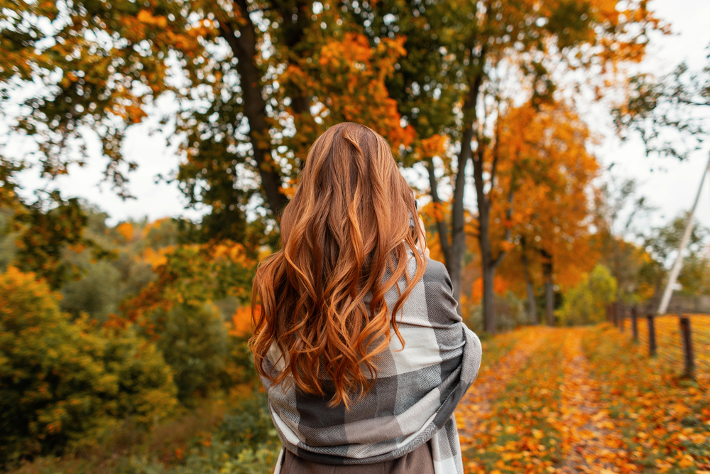 Woman with long red hair outdoors during the fall season